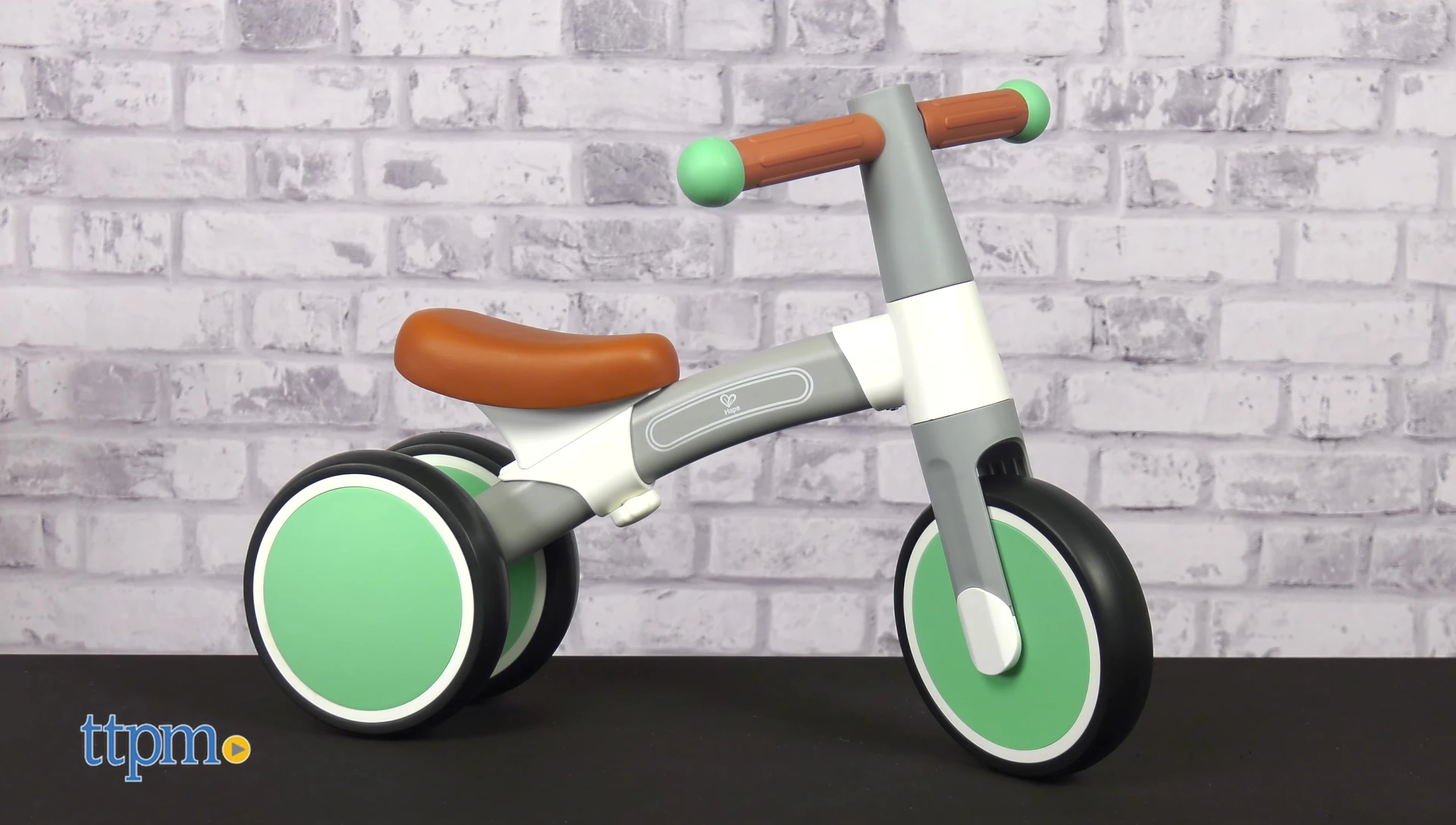 A view of the Hape First Ride Balance Bike, highlighting its gray, white, and green color scheme.