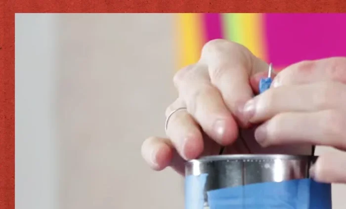 Attach the thumb tack to the top of the wire arch using tape.