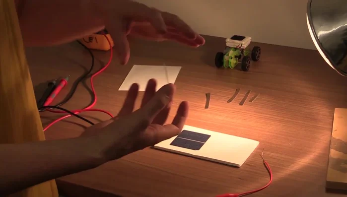 Attach one clip lead to the gray side of the first solar cell using copper tape.