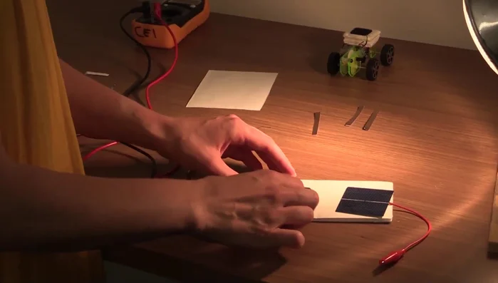 Use copper tape to connect the white contact on the gray side of the first cell to the white contact on the blue side of the second cell.