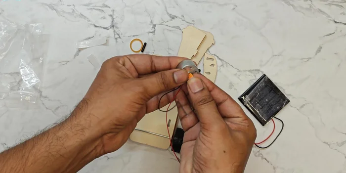 Mount the motor: Secure the motor to the car chassis using the gear and rubber band.