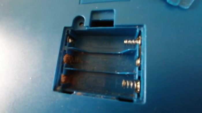 Open the battery compartment and assess the corrosion.