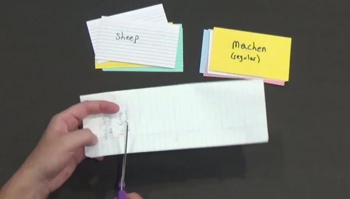 Write the German word on one side and the English translation on the other side, separated by a cut to allow for flipping.