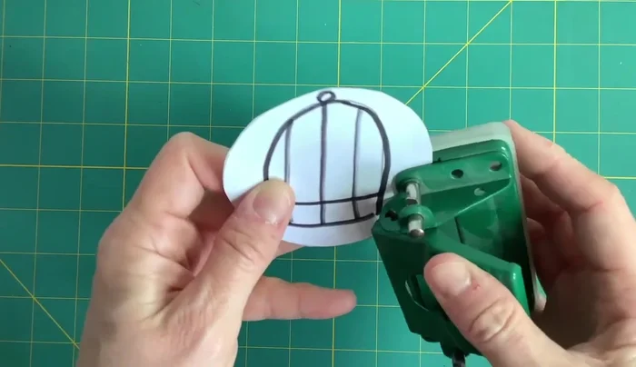 Cut your wool or string into two pieces and thread each piece through the holes, tying a knot at the end.