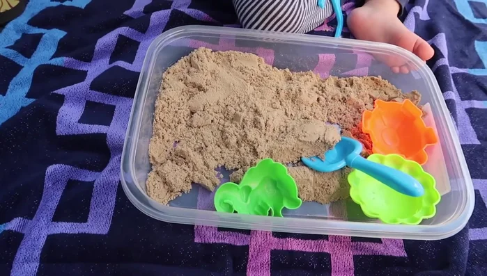 Provide kinetic sand in containers.