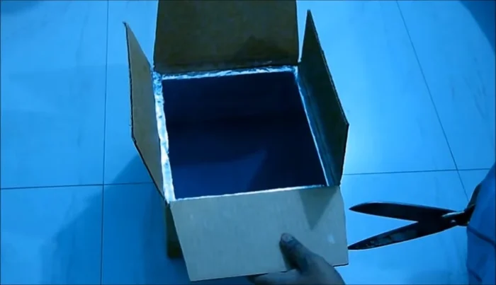 Prepare and attach the top cover: Cut a top cover for the box, leaving a 2-cm overhang. Attach a glass to the top using tape and glue. Add a handle for opening.