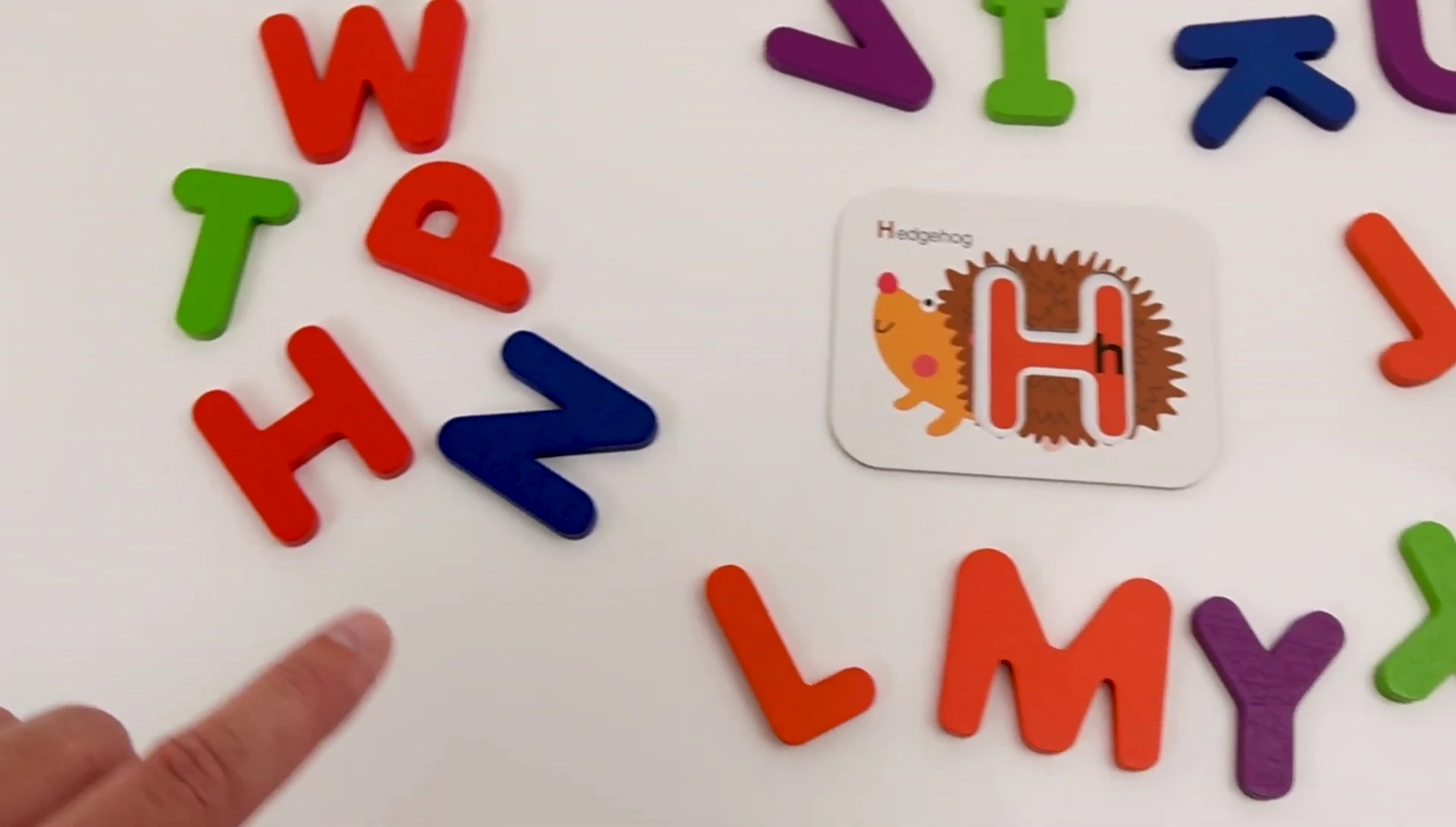 The child discovers the letter 'H' block.