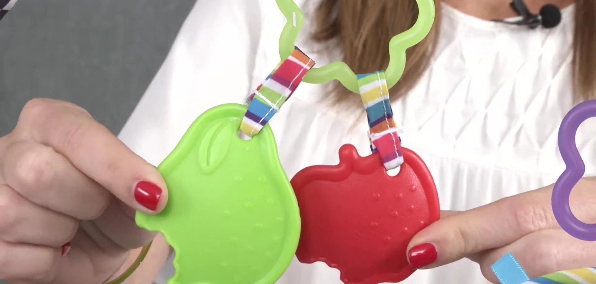 Close-up view of the included toys: apple and pear teethers, mirror, and plush butterfly.