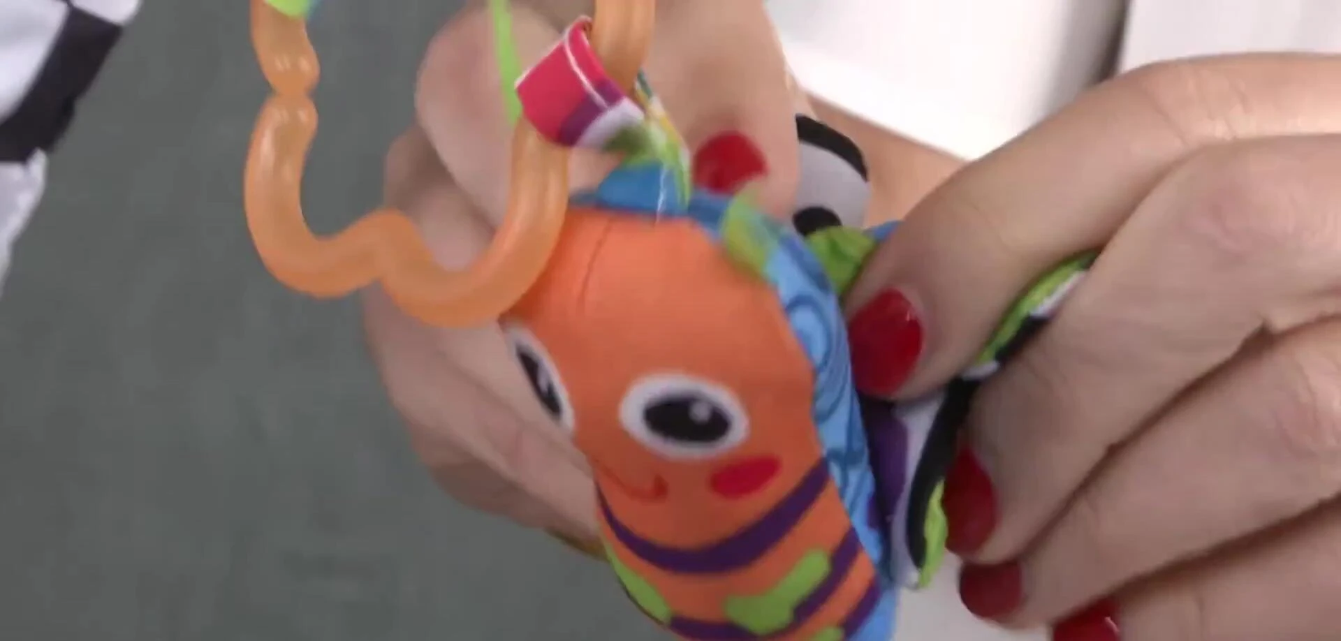 Baby reaching for one of the hanging toys while on their back.