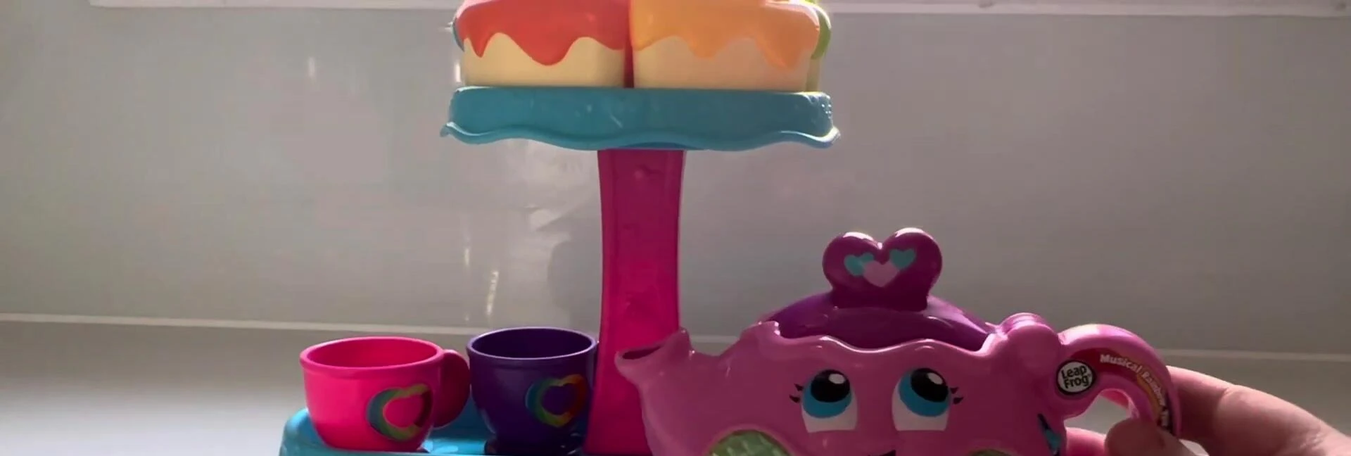 Child interacting with the tea set, demonstrating tea pouring and cake selection