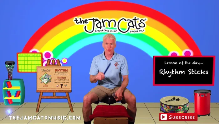 Playing rhythm sticks on a surface. Use a towel to reduce noise if playing on a hard surface.