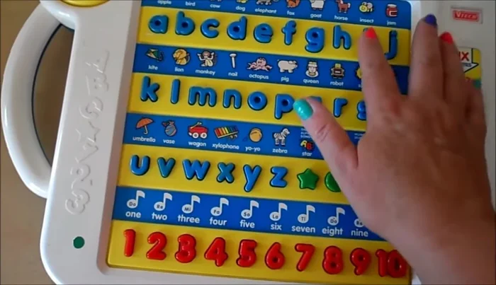 Practice letter recognition: The toy asks 'Where is the letter [letter]?' and the child points to it.