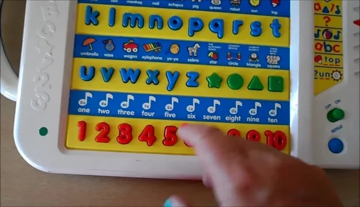 Practice number recognition: The toy asks 'Where is the number [number]?' and the child points to it.
