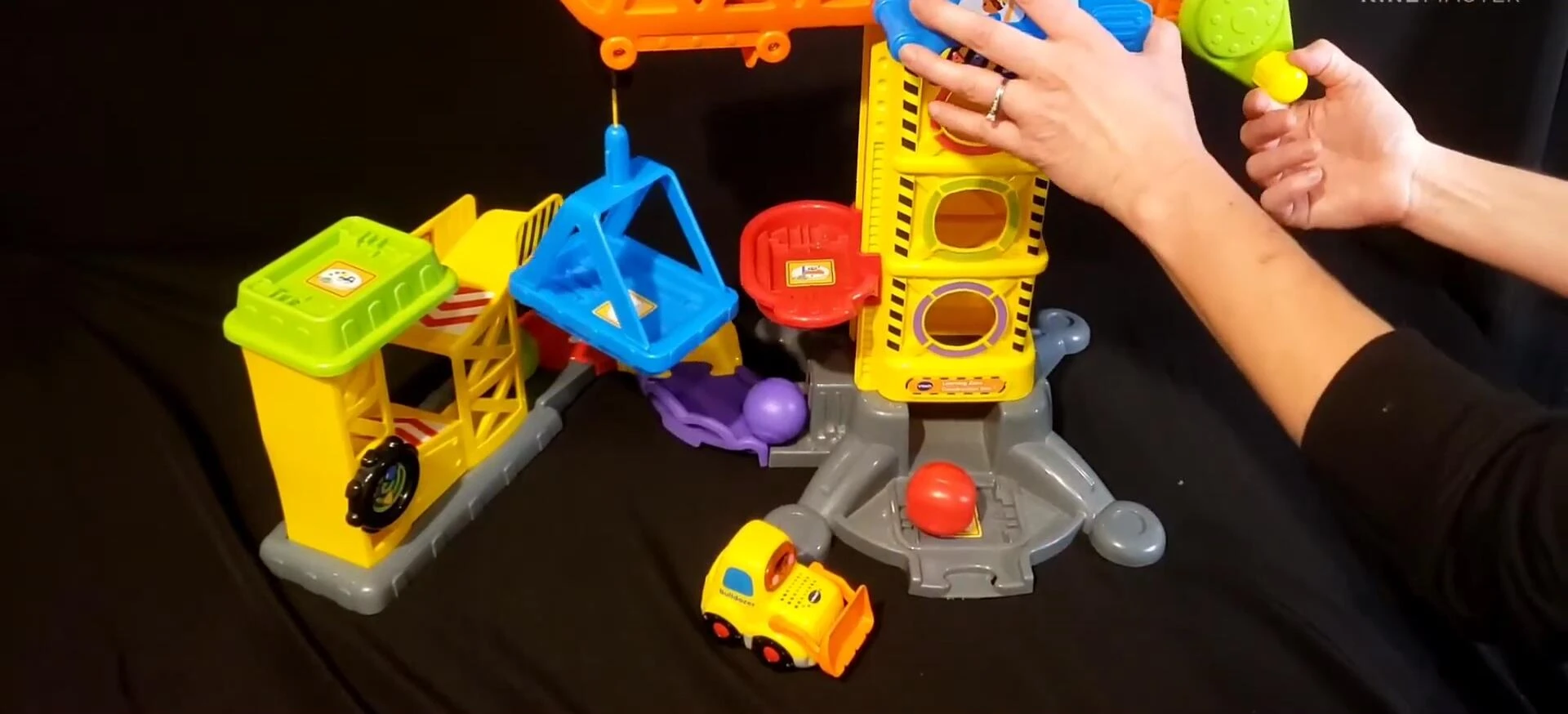 Child playing with the swinging piece of the set, demonstrating gross motor skill development.
