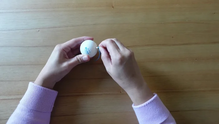 Insert the toothpick into the ping pong ball until the rubber band loop is completely inside.