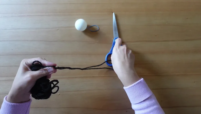 Cut a one-foot length of string and tie it to the rubber band.